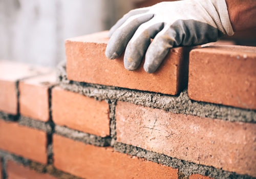 Close up of industrial bricklayer installing bricks on construction site