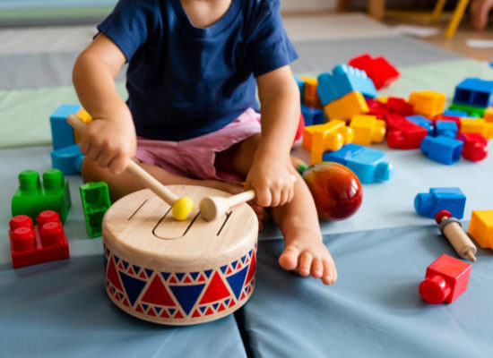 Little boy having fun and playing wooden toy drum